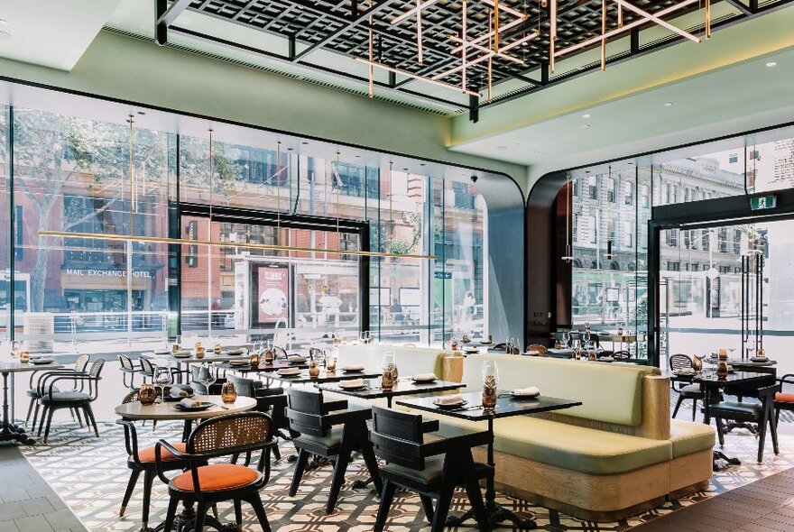 Interior of Miss Mi restaurant during the day showing large windows looking out onto the street, banquette seating, and tables set up for a lunch service.