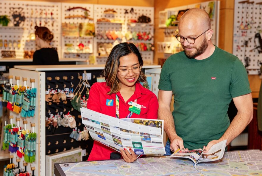 Two people in the Fitzroy Gardens Visitor Centre looking at brochures. 