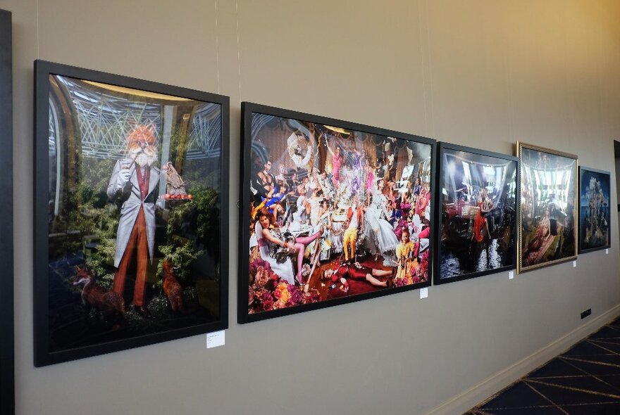 A white wall in a room lined with large scale framed photographic works.