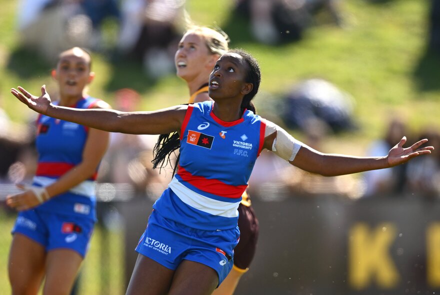 A Western Bulldogs AFLW player celebrating with her arms outstretched either side of her on the field.