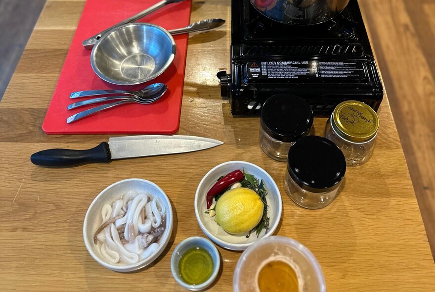 A selection of ingredients and cooking tools to make a calamari antipasto dish.