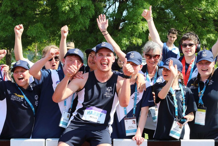 Athletes from the Australian Special Olympics national games, all wearing black and white uniforms and celebrating.