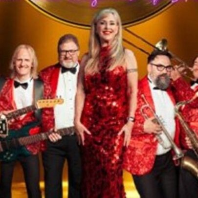 Members of a Motown cover band all wearing red sparkly clothes, some holding musical instruments.
