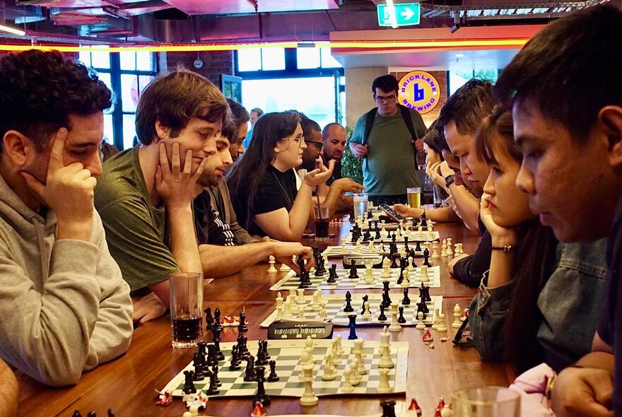 People playing chess at a table in a publike venue.