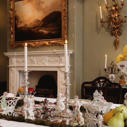 Grand dining room with fireplace, painting, candelabras and set table.