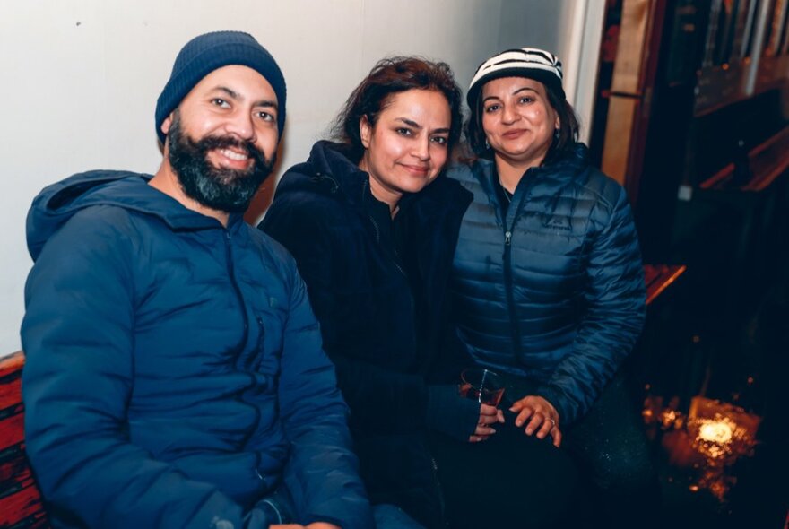 Three warmly-dressed people smiling for the camera.