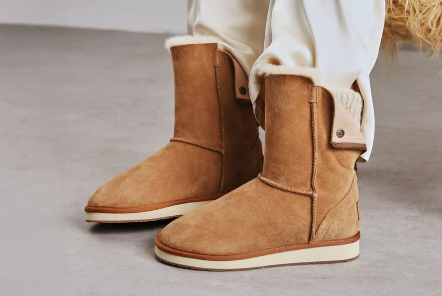 A pair of ugg boots with the tops folded down to reveal a knitted inner.