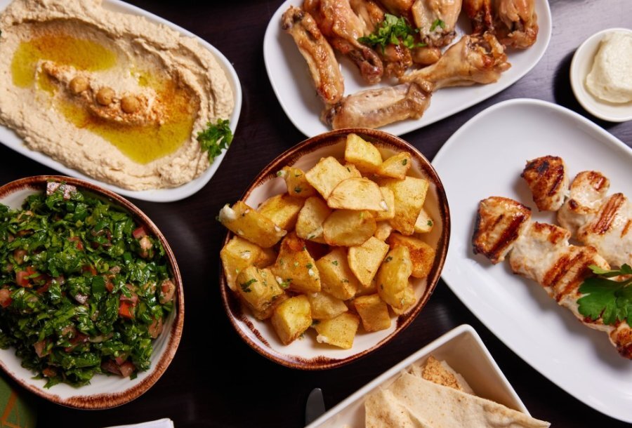A spread of food including potatoes, chicken, and hummus. 