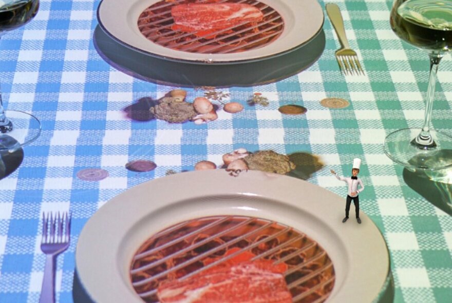 The Petit Chef standing on the edge of a white plate with steak illusion, ingredients scattered on blue gingham tablecloth.