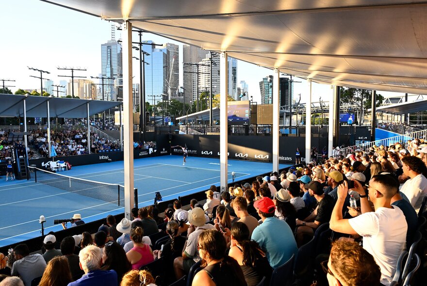 A crown watching a tennis match under cover at the Australian Open.