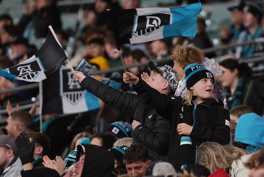 A crowd of Port Adelaide supporters in their colours, with flags.