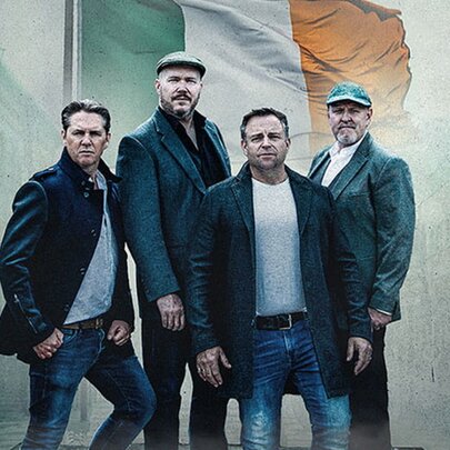 Four members of the Irish folk band The High Kings posing in a serious way with a backdrop of an Irish flag. 