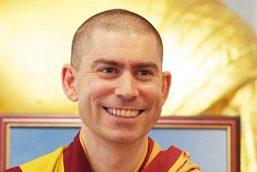 Smiling face of meditation teacher Gen Rabten, surrounded by a warm yellow light.