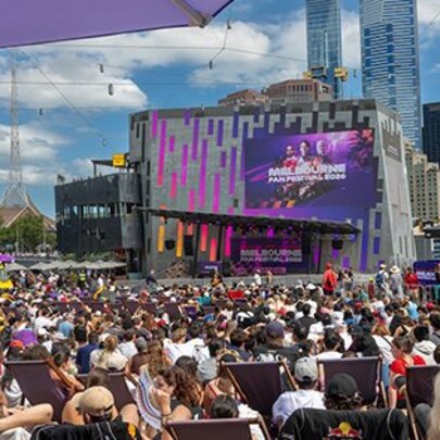 People crowded around the Big Screen at Fed Square on a sunny day.