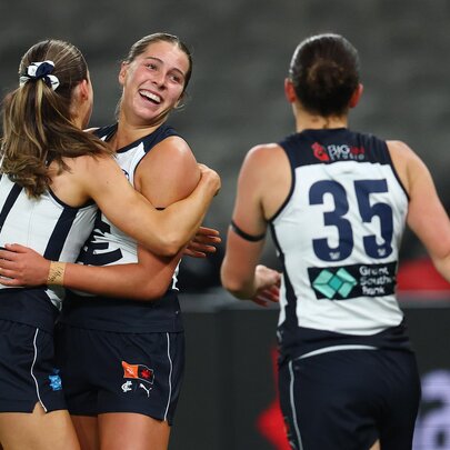 Three Carlton AFLW players celebrating on the field. 