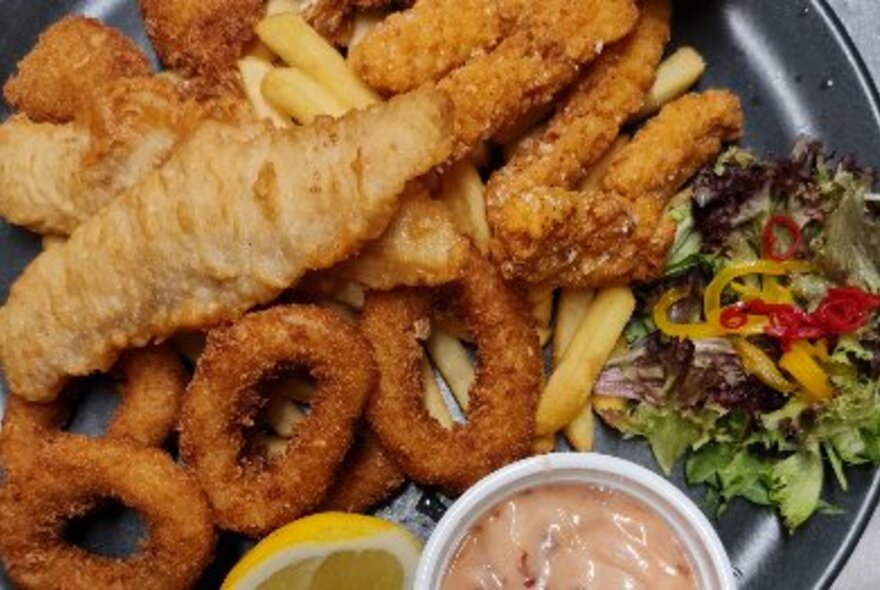 Plate of fried food and salad and condiment.