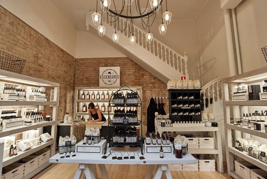 A woman working in a stylish perfume boutique with dark glass bottles.