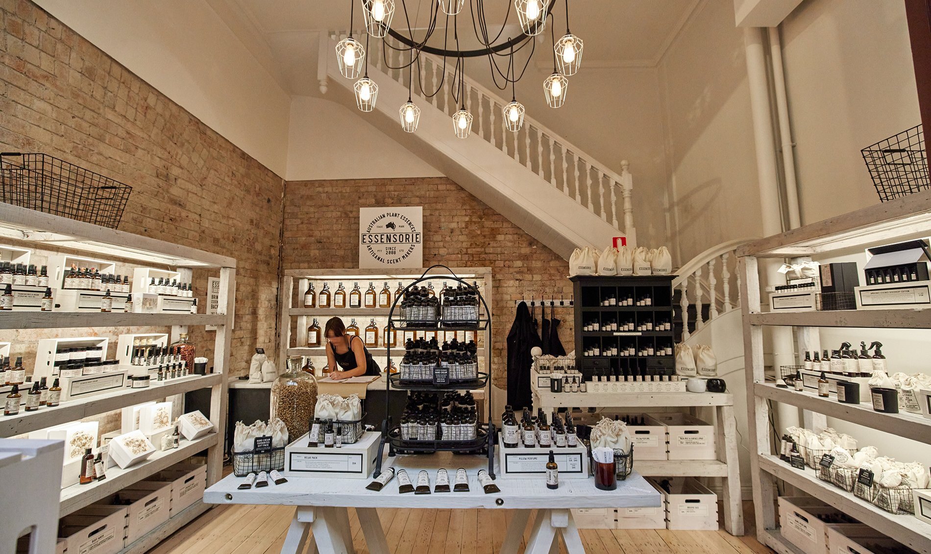 A woman working in a stylish perfume boutique with dark glass bottles.