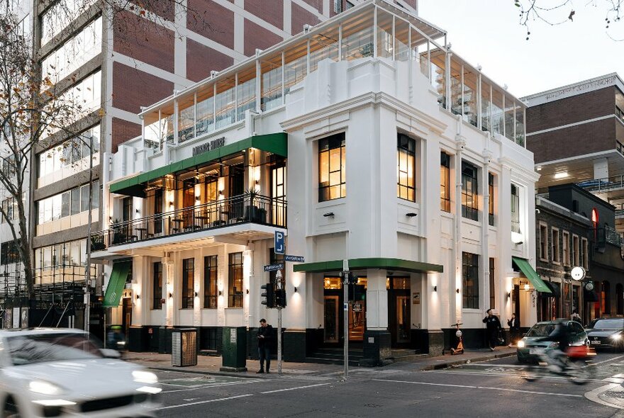 Exterior of Morris House, a white three-level building on a city corner, with 1st-floor balcony on one wide and a glassed-in top floor.