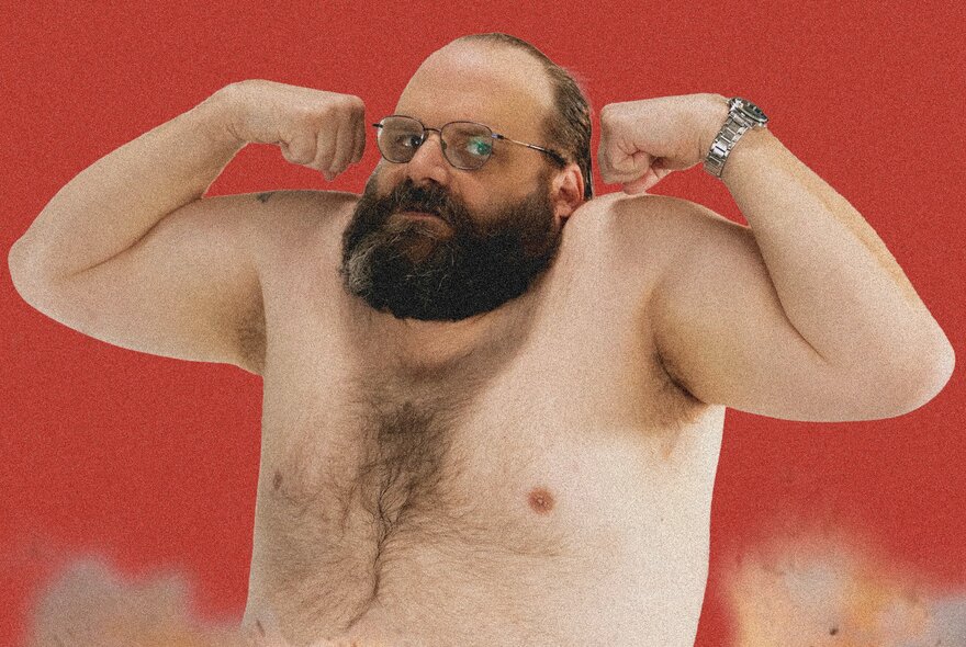 Comedian Greg Larsen, doing a bicep curl while shirtless in front of a red background.