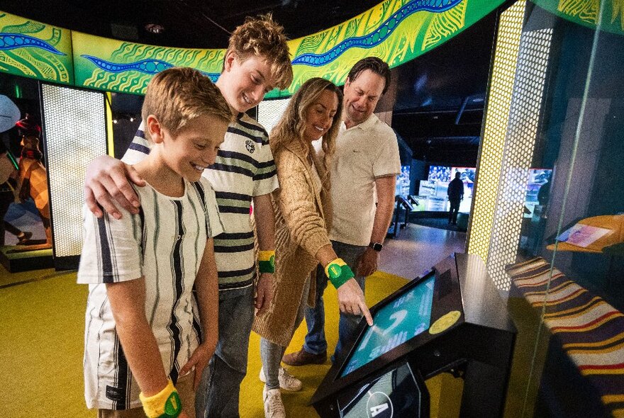 A family looking at a screen in a museum display space.