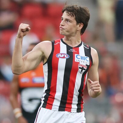 A St Kilda AFL football player on the field during a match, with his fist clenched and raised in a victory pump.