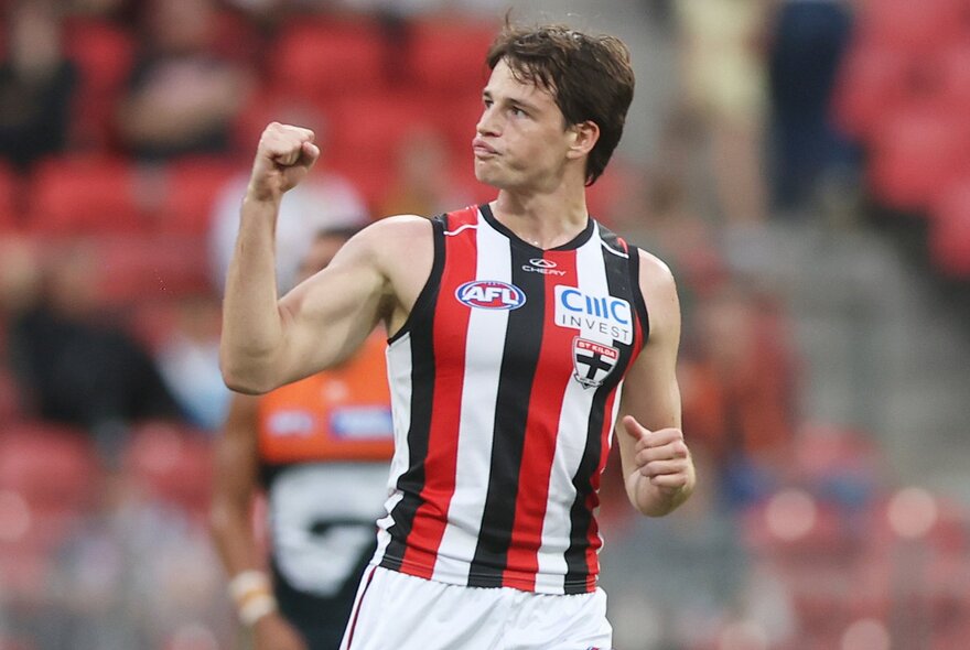 A St Kilda AFL football player on the field during a match, with his fist clenched and raised in a victory pump.