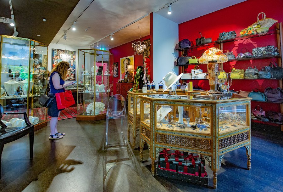 A woman browsing in a boutique filled with hats, bags and jewellery cabinets.