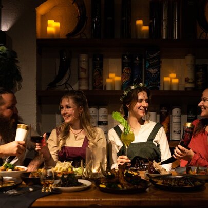 A group of four diners dressed in Viking themed costumes eating at a table in a large hall.