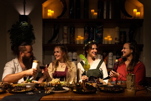 A group of four diners dressed in Viking themed costumes eating at a table in a large hall.