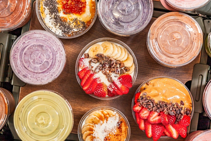 Looking down from above at a selection of smoothies and acai fruit bowls on a table.