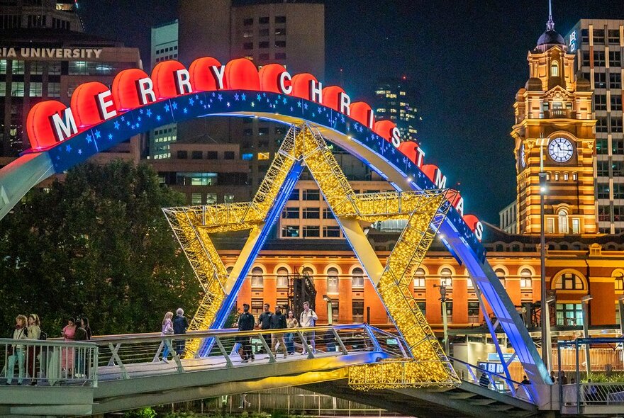 A glowing star decoration on Evan Walker Bridge with Flinders Street Station visible in the background.