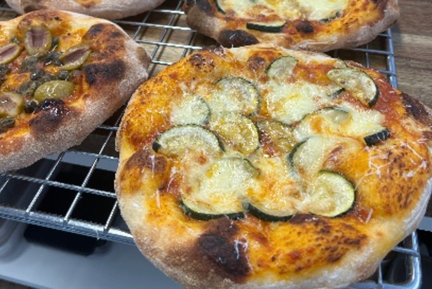 A large cooling rack with pizzas resting on it.