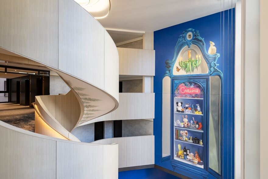 White spiral staircase at Hotel Indigo, with a blue feature wall and a painted mural.