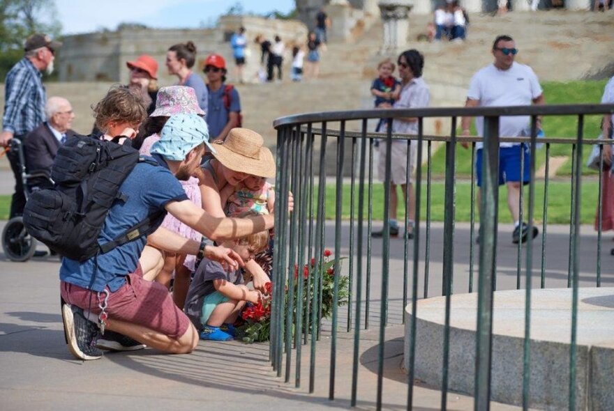 People, bent, laying wreaths at Shrine of Remembrance.