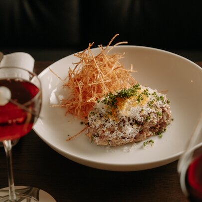 A restaurant dish beautifully presented next to a wine and cocktail.