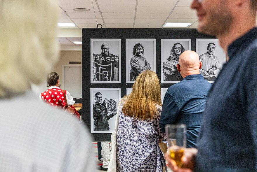People in a gallery space looking at portraits displayed on boards.