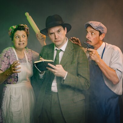 A theatre production featuring three actors dressed in mid-20th-century period costumes against a dark, moody background.