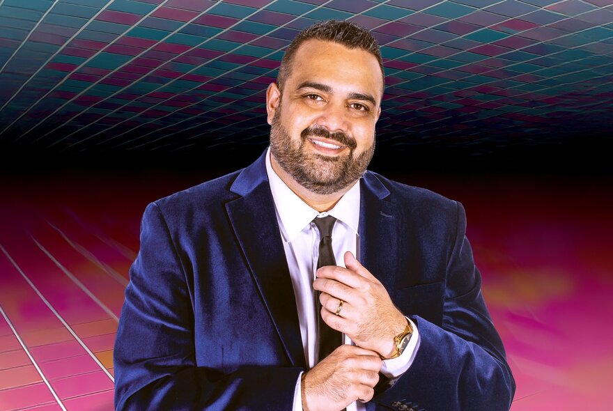 Comedian Dane Simpson, pulling his cuff, wearing a jacket and tie.