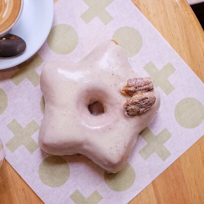 A star shaped donut with a pink glaze and a pecan on top.