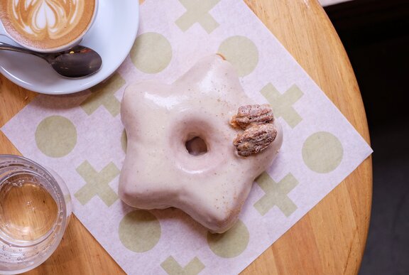 A star shaped donut with a pink glaze and a pecan on top.