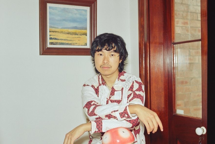 Michael Sun, his arms folded, in front of a glass door and framed artwork.