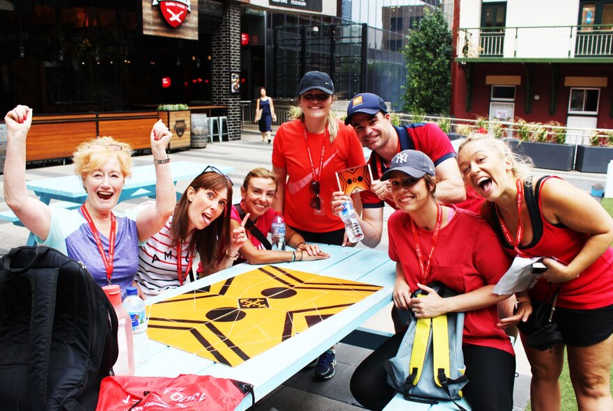 A team of people at a challenge checkpoint, completing a large puzzle on a table, as part of a race though the city of Melbourne.