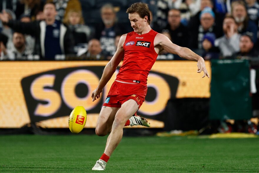 A Gold Coast Suns AFL player kicking a yellow football during a game.