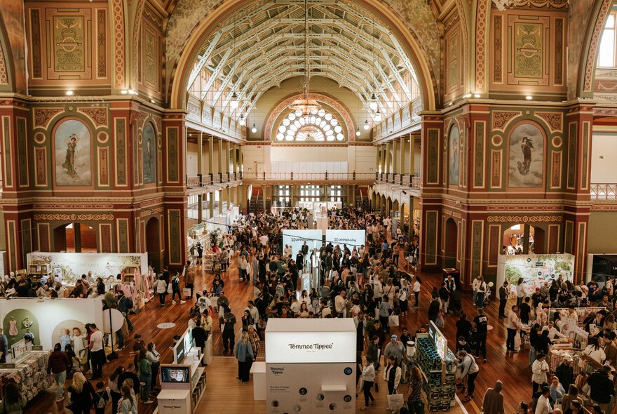 The interior of the Royal Exhibition Building showing it's main archway, with people gathered for an expo. 