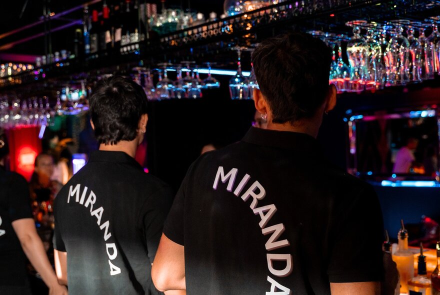 Two bar staff at Miranda Bar wearing black t-shirts with the word MIRANDA printed in white letters on the back.