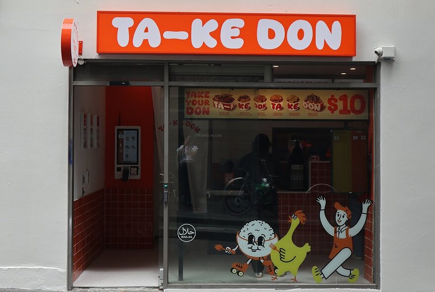 The shopfront of Ta-Ke Don, Thai-Japanese fusion takeaway shop, with its vibrant orange signage