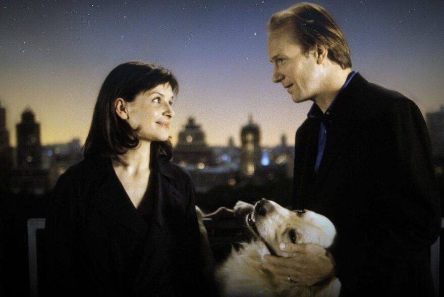 Juliette Binoche and William Hurt (who is patting a Golden Retirever) in a still from the movie A Couch in New York. 