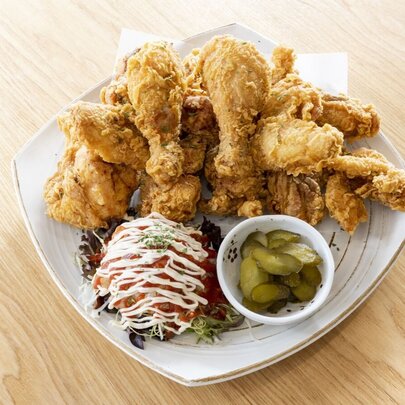 A plate of Korean Fried Chicken with a salad and pickles.