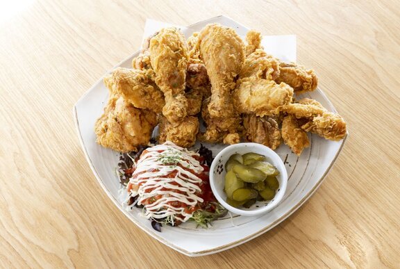 A plate of Korean Fried Chicken with a salad and pickles.